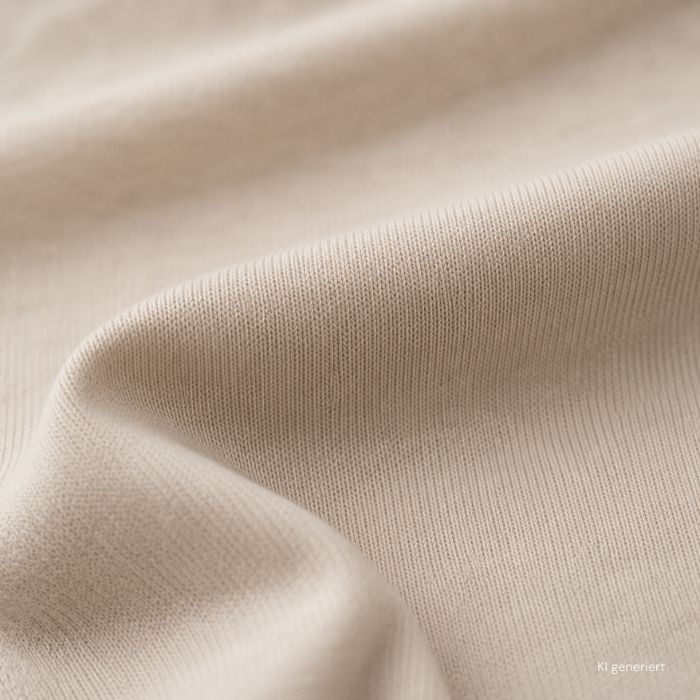 Nahaufnahme eines hellen Single-Jersey-Stoffes mit feiner, gleichmäßiger Strickstruktur und weichen Stofffalten.